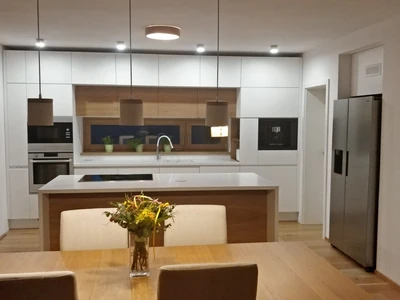 Lakovaná bílá kuchyňská linka v kombinaci s dubovými dýhovanými dvířky, corianovou pracovní deskou a varnou deskou Bora PURE